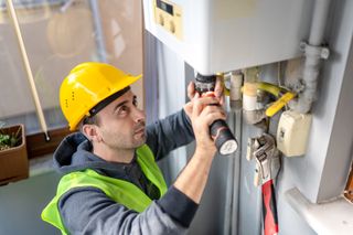 man fixes combi boiler gas boiler ban