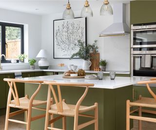 kitchen with green island unit, cabinets, white worktop and wooden stools