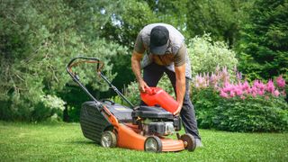 man filling up petrol lawn mower