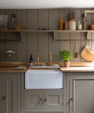 mushroom coloured utility room with wall panelling and shelving with rail fitted underneath