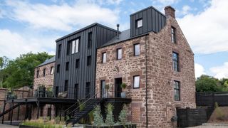 A brick three storey house with a black patio and dormer window